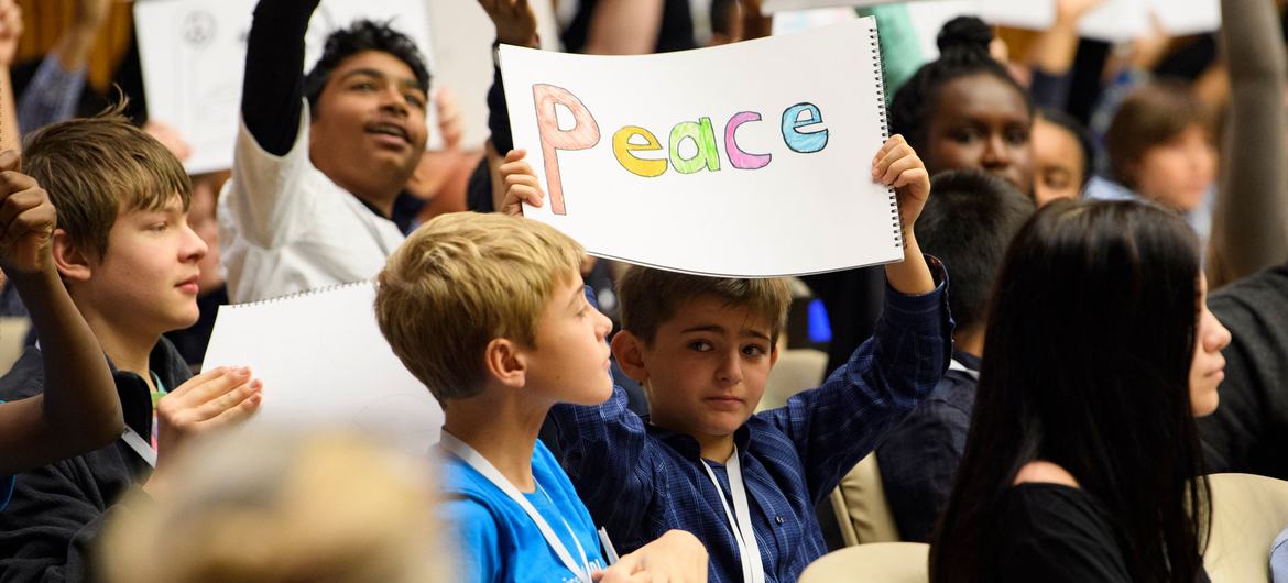 Během speciální akce pořádané u příležitosti Světového dne dětí drží mládež z celého světa znamení vyzývající k míru.